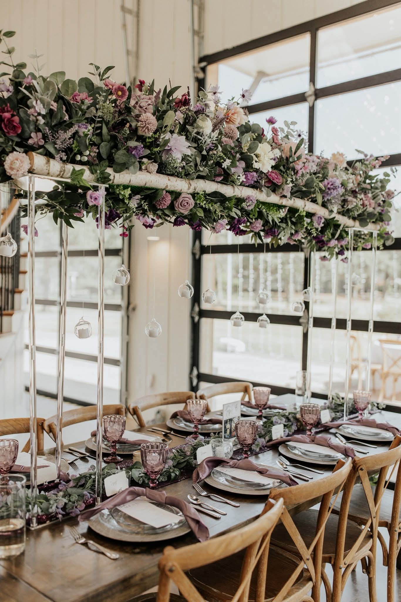 Elevated floral installation with hanging globe terrariums