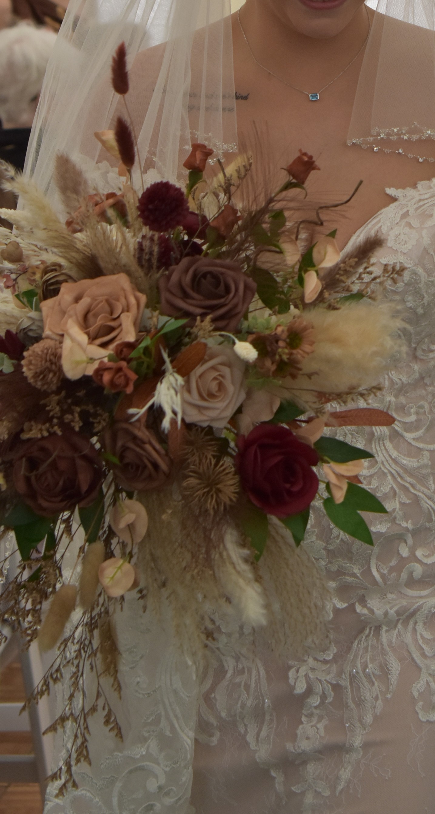 Bride holding cascading bouquet with burgundy and pampas