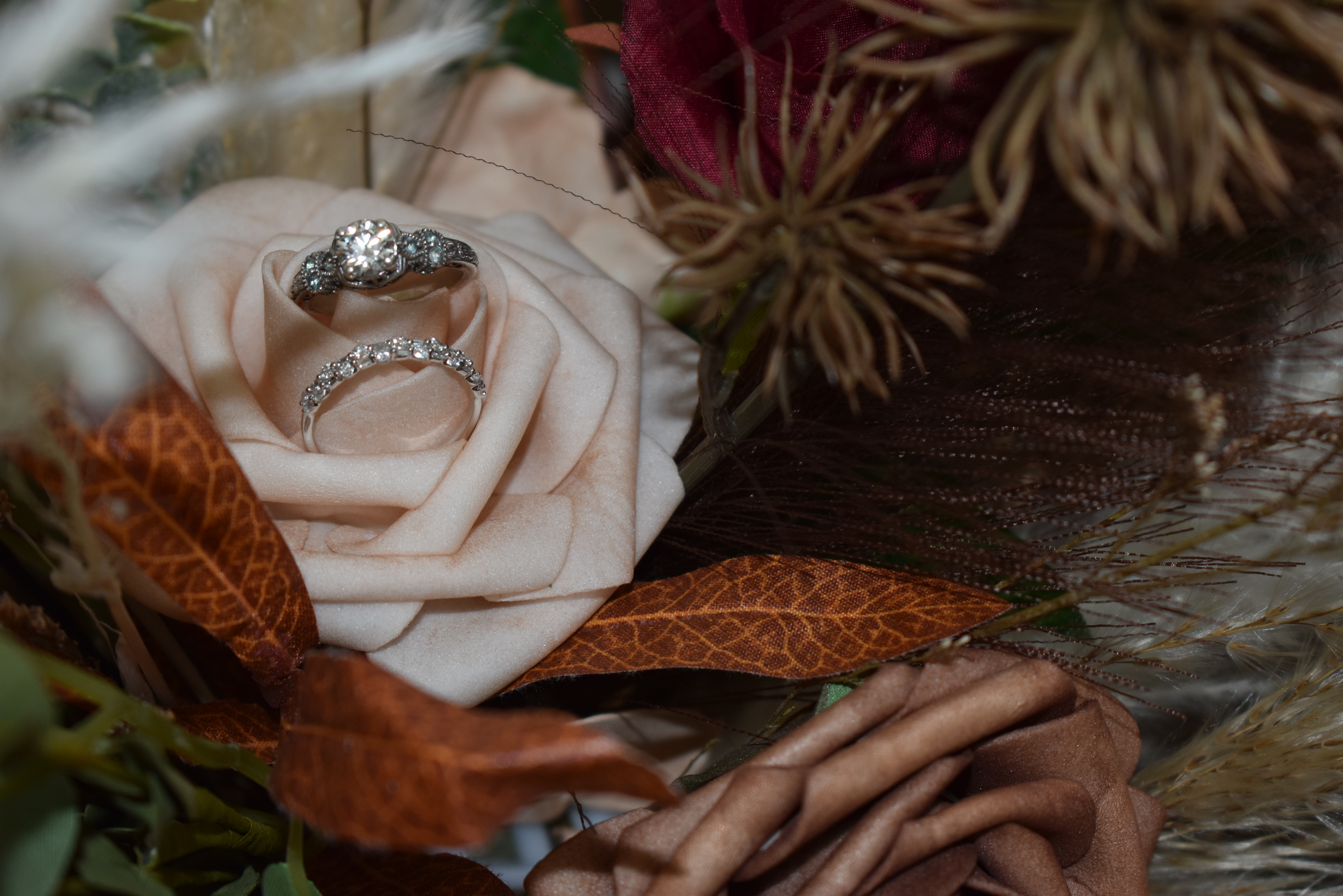 Wedding rings resting on blush faux rose